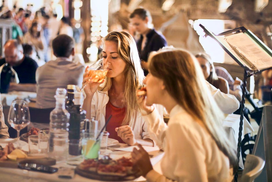 Friends sharing drinks and food at a busy restaurant table